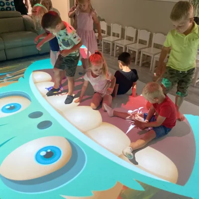 Children playing together on a colorful interactive floor projection with educational activities