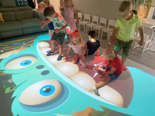 Children playing together on a colorful interactive floor projection with educational activities