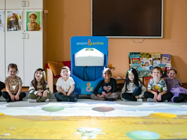 Group of children sitting around an Interactive Floor System with educational games projected on the floor