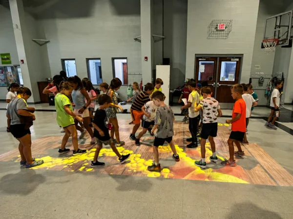 Children playing educational games on an Interactive Floor System in a school gym