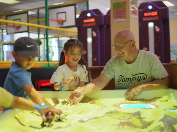 Children and an adult exploring an interactive AR sandbox together