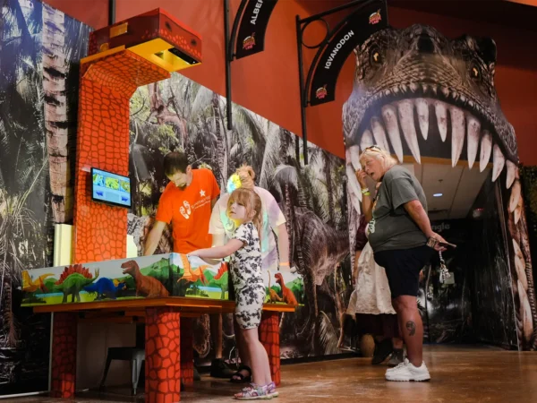 Child exploring an interactive AR sandbox in a dinosaur museum exhibit