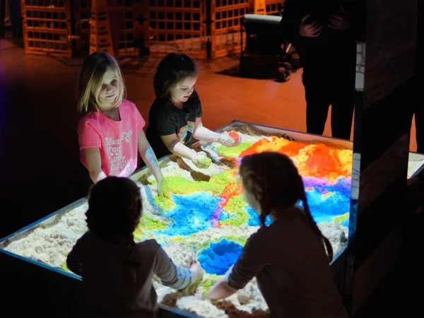 Children shaping sand and exploring colorful augmented reality terrain